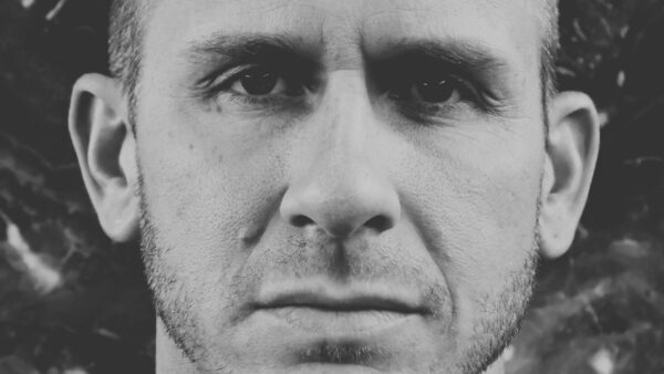 A man looking directly into your eyes, black and white background , you can see the emotion in his eyes .